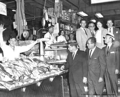 Store clerk selling fish to patrons in La Marqueta may-64