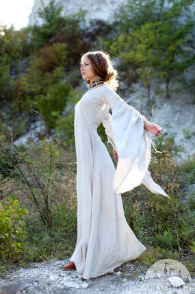Lady in long white dress standing in forest clearing