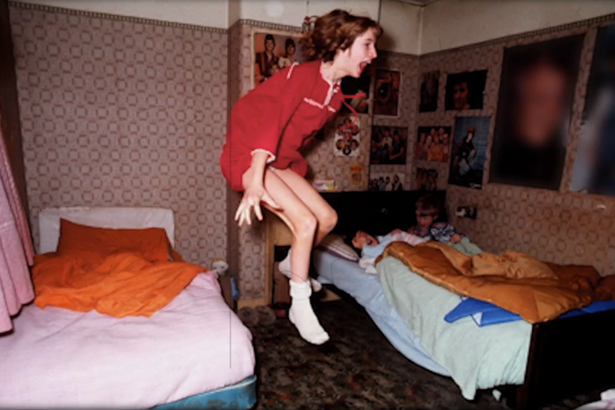 scared girl floating in ait between two beds