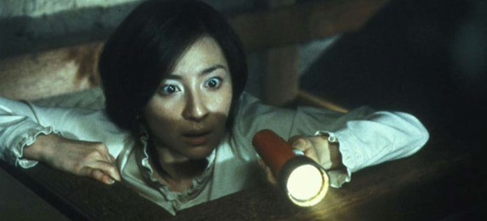 Scared woman with flashlight looking for ghosts